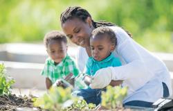 Teacher helping two preschoolers with gardening