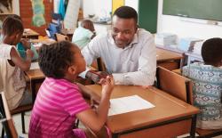 Male teacher helping student in classroom