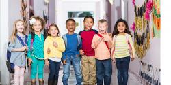 primary school students pose for a photo in a line wearing backpacks 