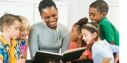 teacher reading a book to a group of children 