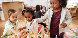 A classroom of children playing with wooden blocks 