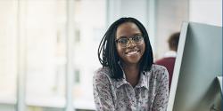 A woman behind a desktop smiles at the camera