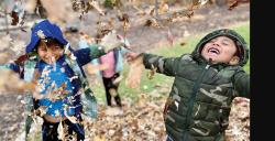 children playing together in fall leaves