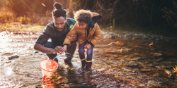 a child and parent playing in a stream