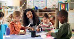 An early childhood educator working with students in a classroom