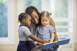 A teacher reading to two young chidren