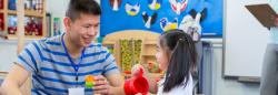 Child and teacher playing with toys in classroom