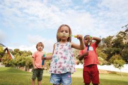 Children blowing bubbles in field