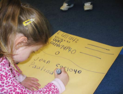 Child writing on poster 