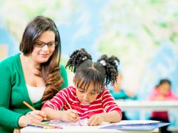 a teacher writing with a child at a table