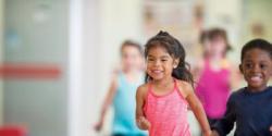 A group of young children run down a hallway