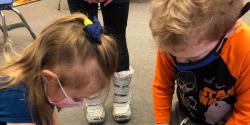 two children looking at a project in a classroom