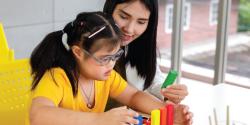 a teacher helping a child play with blocks