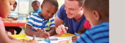 Teacher helping three preschool students with coloring