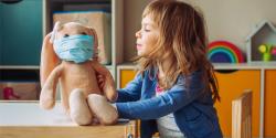 little girl playing with doll and putting a mask on