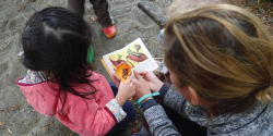 a teacher showing a child a nature book outside
