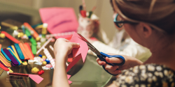 a person cutting a piece of paper around art supplies