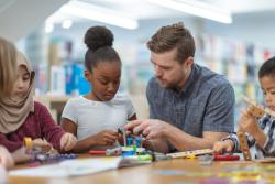 A teacher working with a student on a project in a classroom