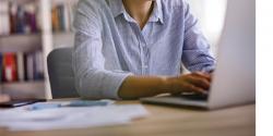 woman sitting at the computer typing on a laptop