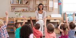 teacher smiling while student raise their hands to participate