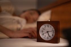 Image of a clock with a woman sleeping in the background