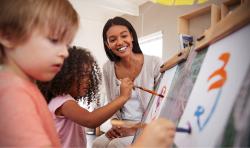 An educator painting with her two students.