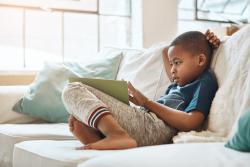 young preschool boy sitting on a couch reading