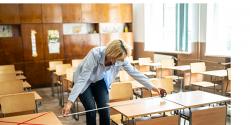 Educator measuring the distance between desk in classroom