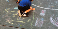 A child drawing with sidewalk chalk.