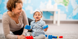 A toddler playing with blocks with a parent.