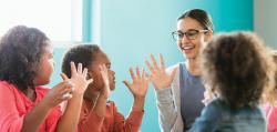 Teacher and three preschool students with hands up