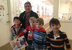 Teacher and students smiling with artwork