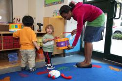 Toddlers in a learning environment playing with female teacher.