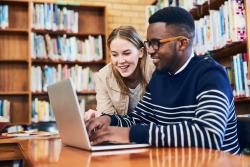 Two young professionals on a computer in the library