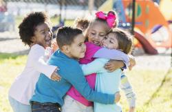 Young children on a playground hugging