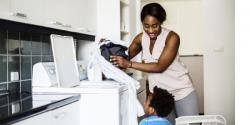 Mother and young son in a laundry room looking at clothing