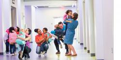 5 parents, each hugging their child in a school hallway