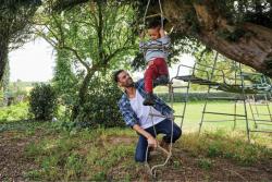 father and son playing on rope swing outside