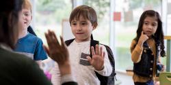 teacher and 3 children greeting each other outside