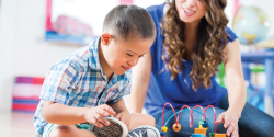 A teacher observes as a child plays with toys.