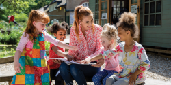 a teacher showing students a book outside