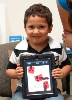 Child showing his artwork on a tablet.