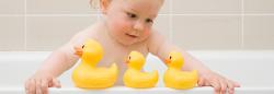 Toddler in the bathtub playing with rubber ducks.