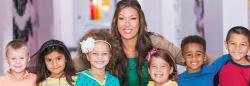 Teacher smiling with a group of young children.