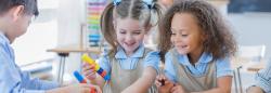 Three students playing with toys in a classroom