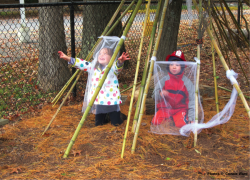 Two children playing outside under  long bamboo poles