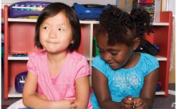 Two girls sitting close to each other, but not talking.