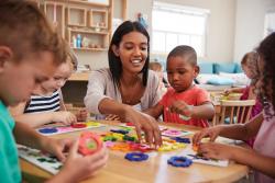 Teacher and diverse students at a table working with flower shapes