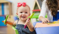 Child holding markers and smiling