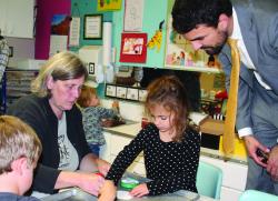 Two adults engage with children in a learning center